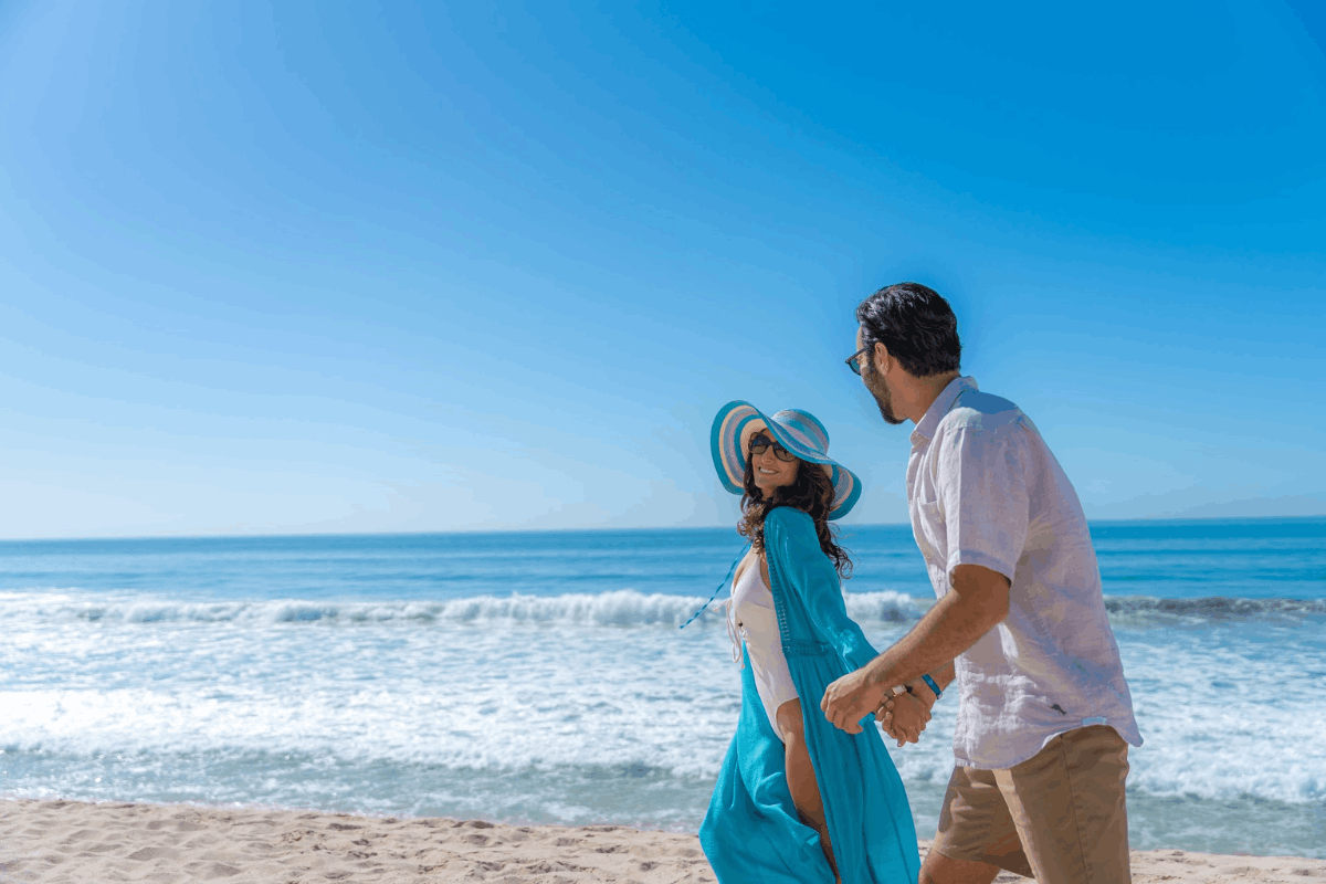 Pareja caminando en la playa de Krystal Grand Los Cabos durante una escapada romántica frente al Mar de Cortés.